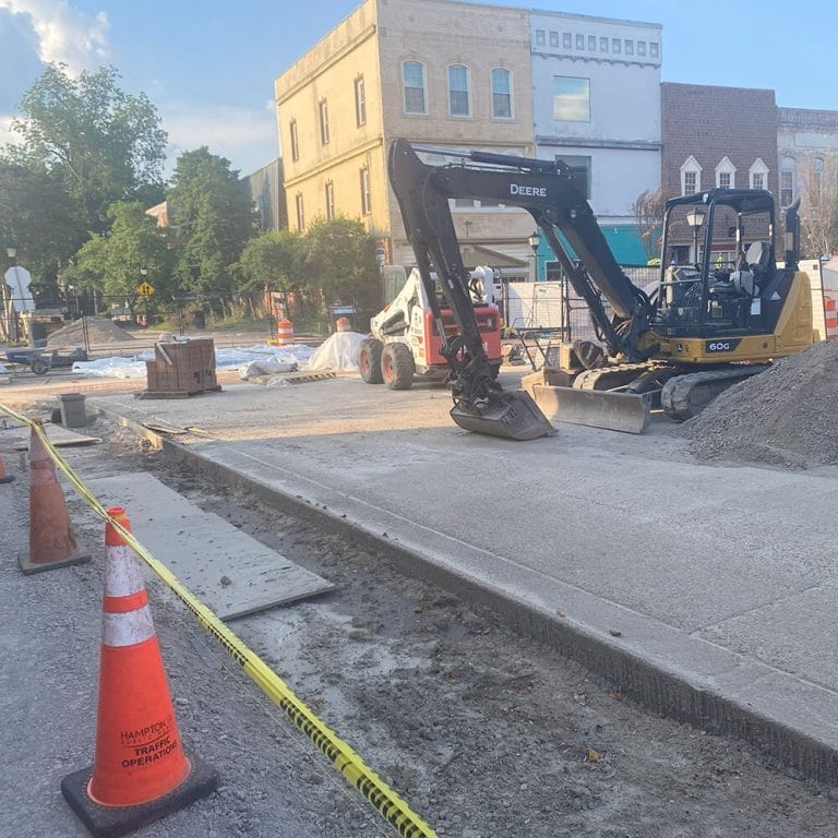 Backhoe tearing up street during road construction